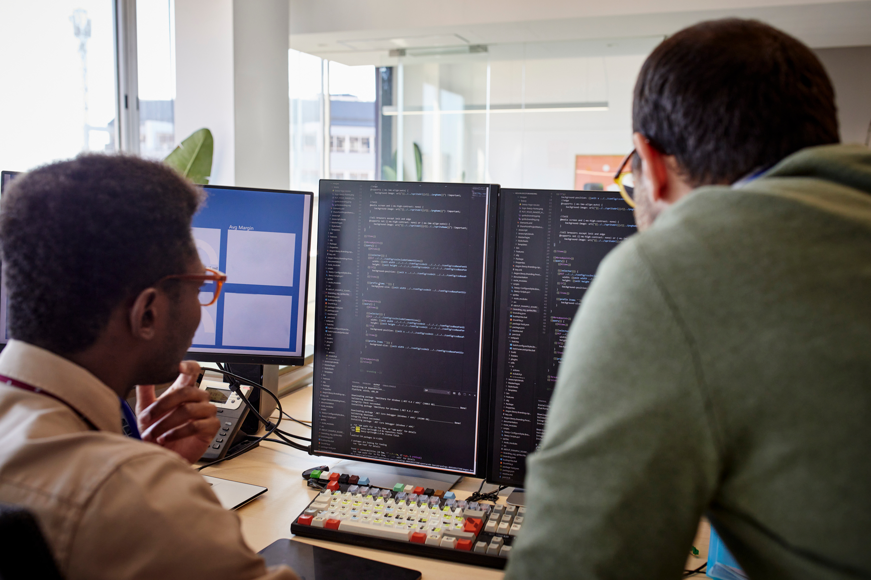 Two males side by side facing a computer screen with code